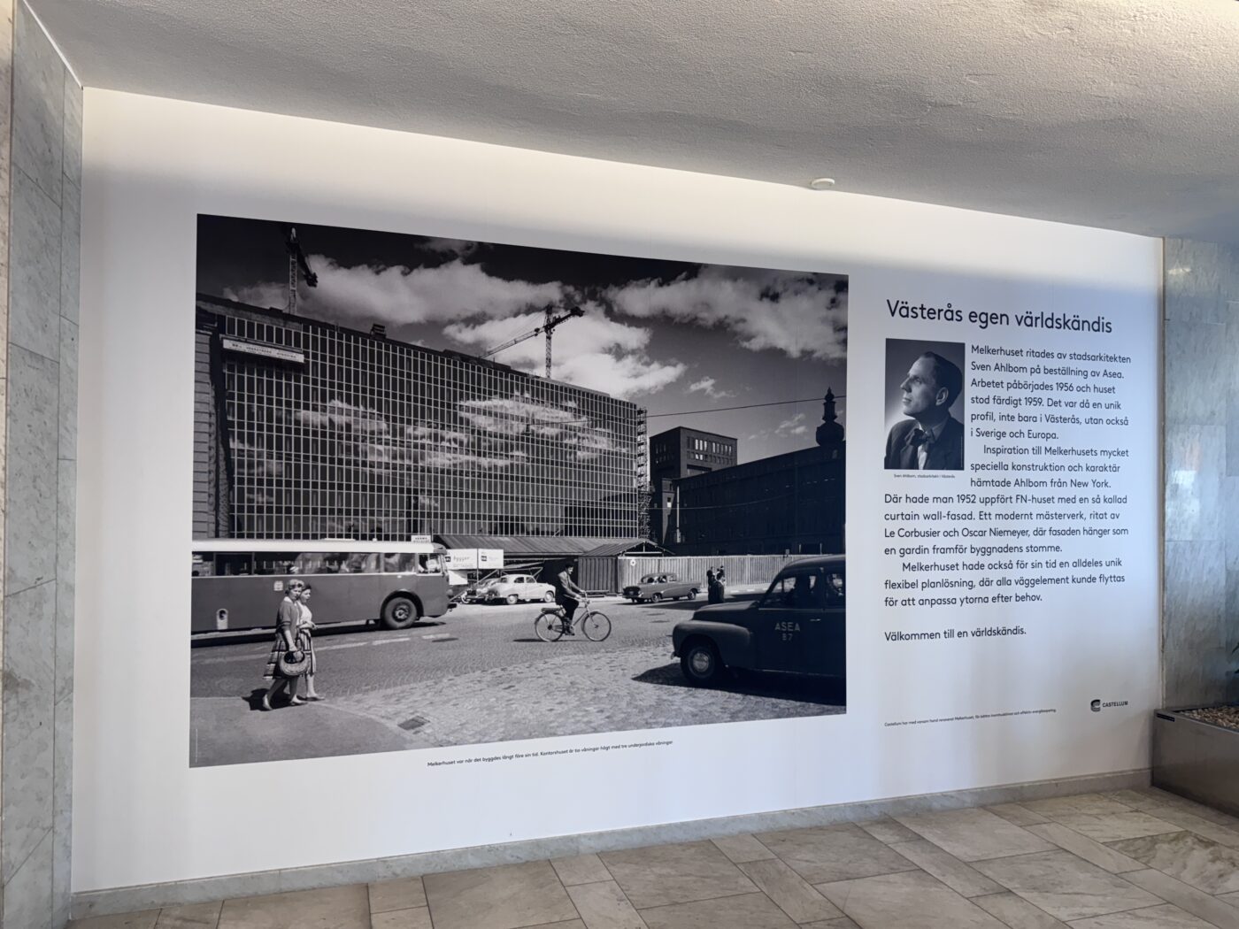 Large black-and-white city scene on an exhibit wall showing cranes and a construction site, with a Swedish text panel to the right titled 'Västerås egen världskändis'.