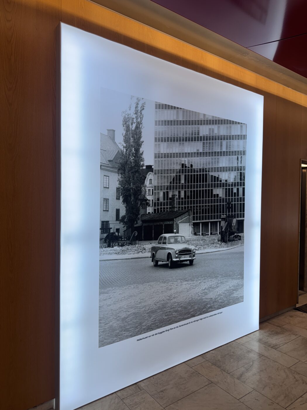 Backlit display panel featuring a black-and-white street scene with a vintage car and historic buildings in the background.